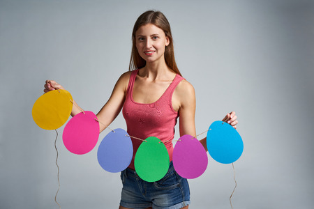 Smiling woman holding a garland of Easter eggs shapeの写真素材