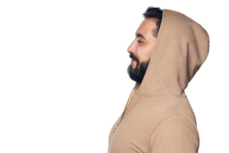 Profile of Hispanic man in casual clothes with hood on, looking forward, over white studio backgroundの写真素材