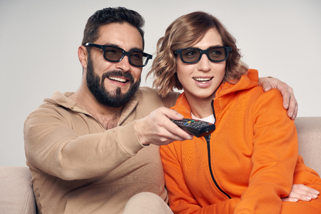 Family watching 3D film on TV, man pointing remote control out of frameの写真素材