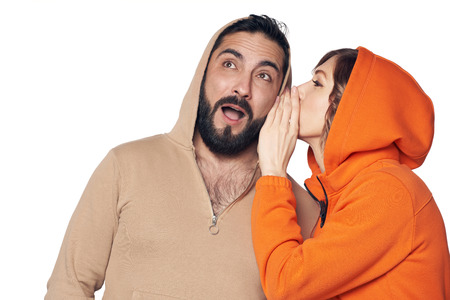 Secret, gossip concept. Young woman whispering a secret to the man. Man is surprised looking awayの写真素材