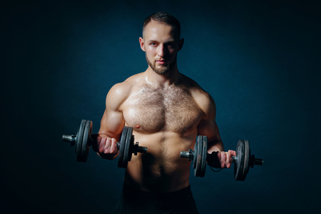 Strong handsome shirtless sport man with dumbbellsの写真素材