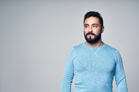 Confident man in blue pullover standing looking to side at blank copy spaceの写真素材