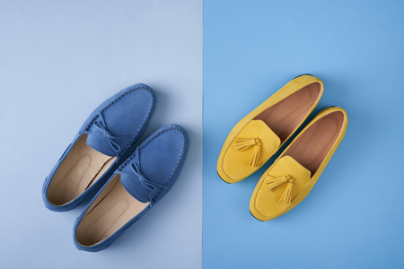 Blue suede man's and yellow woman's moccasins shoes over blue background, top viewの写真素材