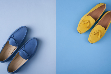 Blue suede man's and yellow woman's moccasins shoes over blue background, top viewの写真素材