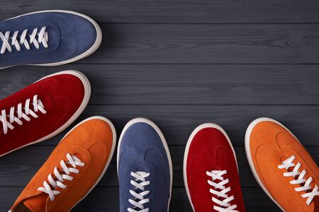 Top view of colorful casual unisex suede sneakers forming a frame with copy space, on grey wooden planksの写真素材
