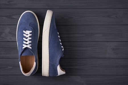 Top view of a pair of casual blue suede trainers on grey wooden planks with copy spaceの写真素材