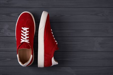 Top view of a pair of casual red suede trainers on grey wooden planks with copy spaceの写真素材