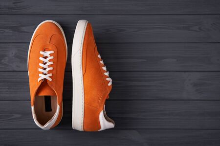 Top view of a pair of orange casual suede sneakers on grey wooden planks with copy spaceの写真素材