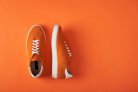 Top view of casual orange suede sneakers on orange background with copy spaceの写真素材