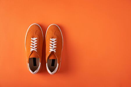 Top view of casual orange suede sneakers on orange background with copy spaceの写真素材