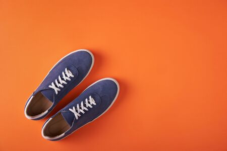 Top view of casual blue suede sneakers on orange background with copy spaceの写真素材
