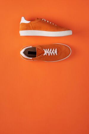 Top view of casual orange suede sneakers on orange background with copy spaceの写真素材