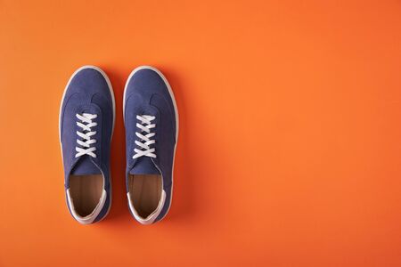 Top view of casual blue suede sneakers on orange with copy spaceの写真素材