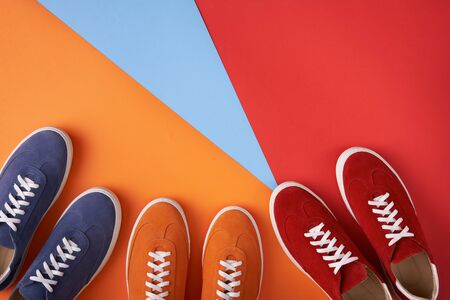 Three pairs of colorful casual unisex suede sneakers standing on multicoloured background, flat lay style with copy space for your textの写真素材