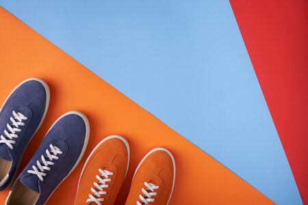 Two pairs of colorful casual unisex suede sneakers standing on multicoloured background, flat lay style with copy space for your textの写真素材