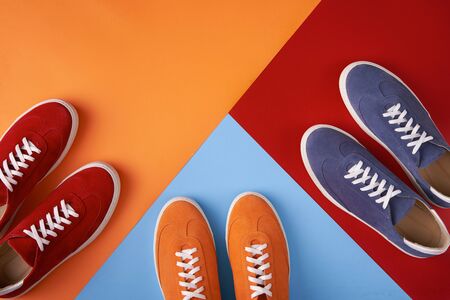 Three pairs of colorful casual unisex suede sneakers standing on multicoloured background, flat lay style with copy space for your textの写真素材