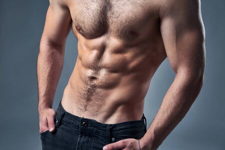 Cropped image of muscular shirtless man posing with hands in pocketsの写真素材