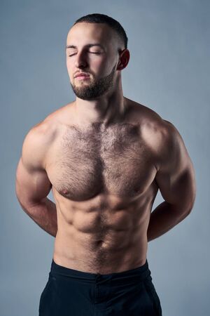 Muscular shirtless man with hands over back, daydreaming with closed eyesの写真素材