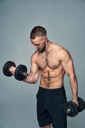 Strong handsome shirtless sport man with dumbbellsの写真素材