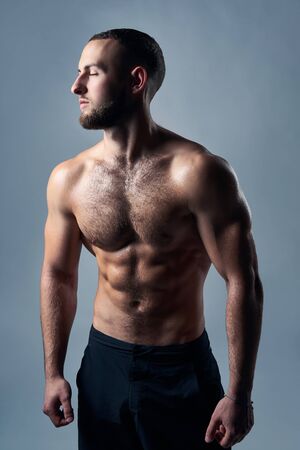 Muscular shirtless man with hands over back, standing with closed eyesの写真素材