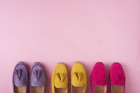 Multicolored suede moccasins shoes standing in line with copy space above, over pink background, top viewの写真素材