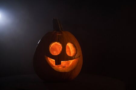 Kind smiling Halloween Pumpkin in dark with white backlightの写真素材