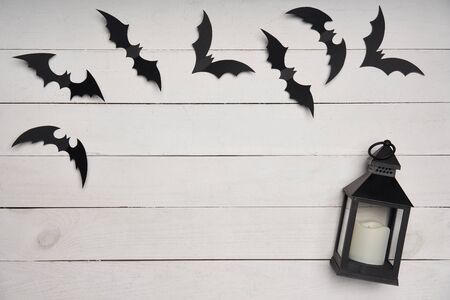 Halloween card. Black paper decoration bats and black lantern on white wooden planks, with blank copy space in centerの写真素材