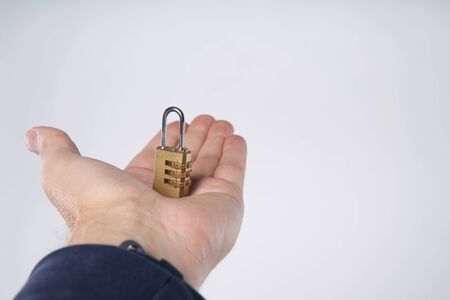 Man's hand holding small combination lock on a palmの写真素材