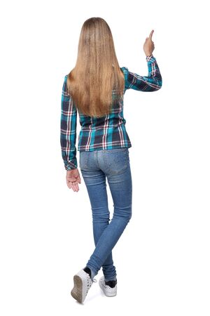 Full length back view of teen girl in checkered shirt standing casually over white background pointing to sideの写真素材