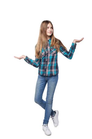 Full length teen girl in checkered shirt standing casually over white background with two opened hand palms with blank copy spacesの写真素材