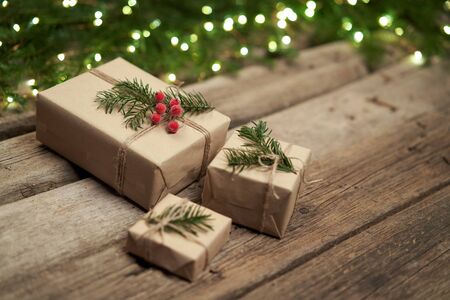 Christmas gifts with fir branches with lights on rough weathered wooden planks