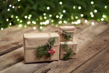 Christmas gifts with fir branches with lights on rough weathered wooden planks