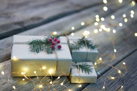 Christmas gifts with garland lights on rough weathered wooden planks
