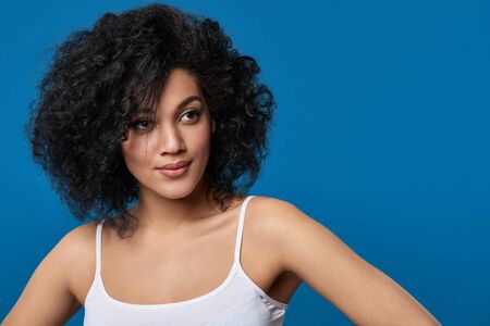 Closeup portrait of beautiful mixed race woman looking to side at blank copy space, over blue backgroundの写真素材