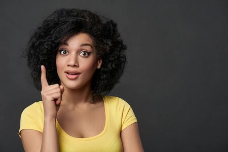 Surprised woman with finger up, over gray studio backgroundの写真素材