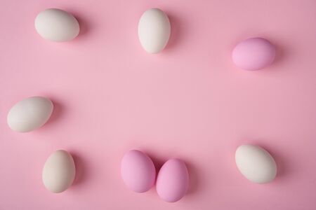 White and pink Easter eggs scattered on pink background with copy space above. Minimalist cardの写真素材