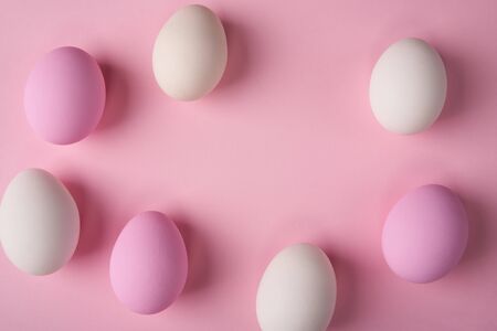 White and pink Easter eggs scattered on pink background with copy space above. Minimalist cardの写真素材