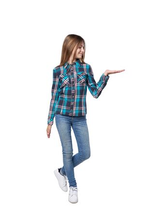 Full length teen girl in checkered shirt standing casually over white background holding copy sape on her open hand palmの写真素材