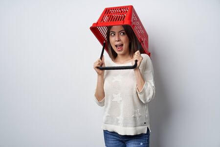 Crazy woman putting empty shopping basket on her head, looking away shoutingの写真素材