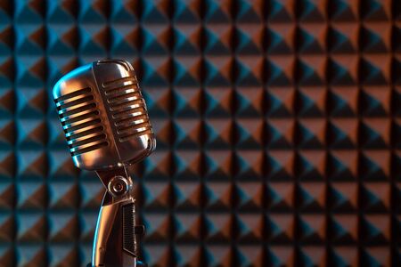 Retro microphone on acoustic foam panel background, colorful light, closeupの写真素材
