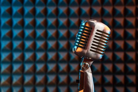Retro microphone on acoustic foam panel background, colorful light, closeupの写真素材