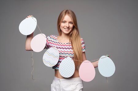 Smiling girl holding a banner of Easter eggs shapeの写真素材