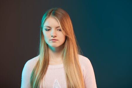 Portrait of young thoughtful female, studio shot with colorful backlightの写真素材