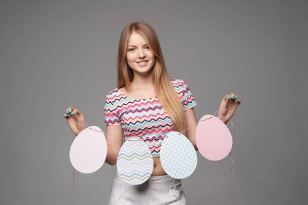 Smiling girl holding a banner of four Easter eggs shapeの写真素材