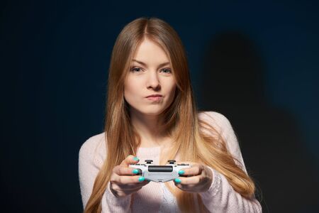 Computer game competition. Gaming concept. Focused girl playing video game with joystick squeezing her lipsの写真素材