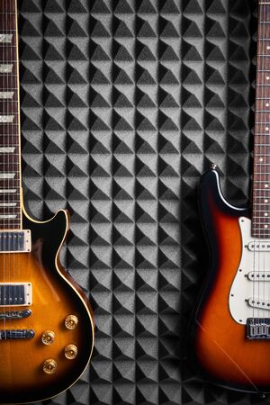Top view of two electric guitars on acoustic foam panel background, with copy space betweenの写真素材