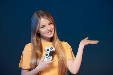 Gamer girl. Smiling young woman holding joystick holding open palm showing blank copy spaceの写真素材