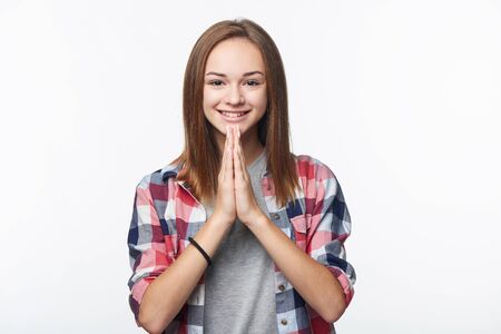 Portrait of smiling teen girl greeting with a gesture with palms pressed together in a prayer-like fashionの写真素材