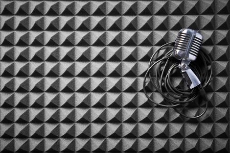 Retro microphone with cable lying on acoustic foam panel background, flat layの写真素材