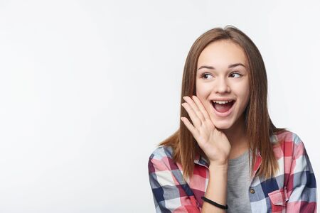 Surprised teen girl looking to side at blank copy space screaming, studio portraitの写真素材